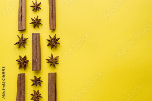 composition of star anise, cinnamon sticks on yellow background. Abstract flat pattern, top view photo