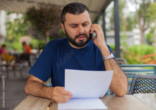 Young man talking on the phone and looking at papers