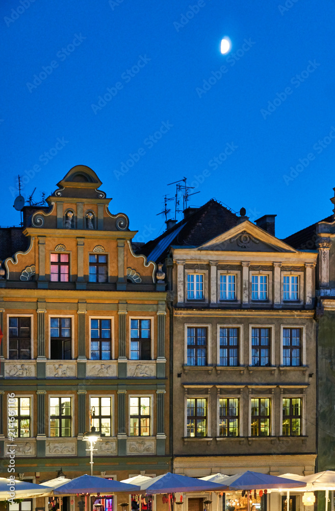 moon and facade of tenements in the Old Market Square at night in Poznan.