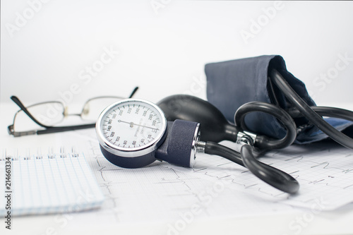 Sphygmomanometer on the working table of a cardiologist. Tonometer, electrocardiogram and notepad for records.