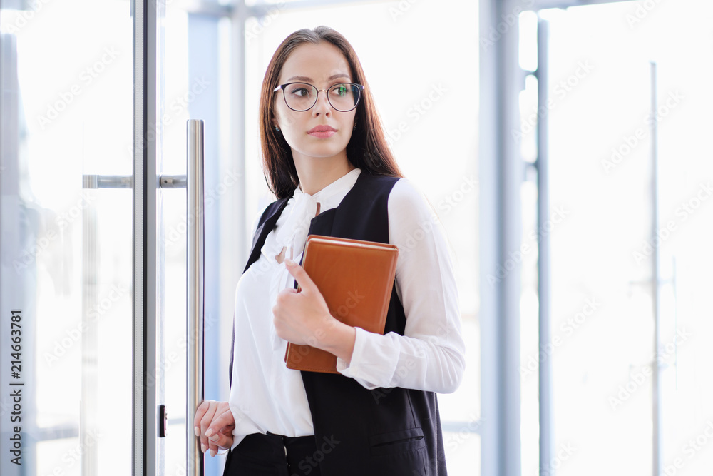 A young beautiful girl in eyeglasses enters glass office door. A young beautiful girl in eyeglasses enters glass office door.