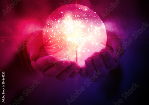 Magic glowing ball with a flash of light in women's hands on an abstract dark background.