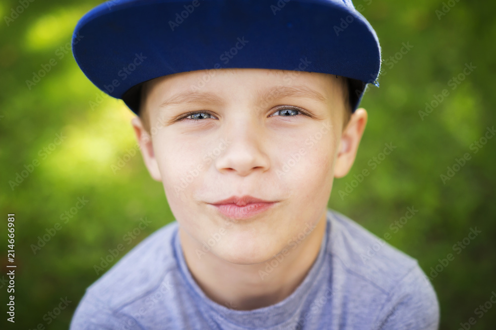 Portrait of beautiful little white boy in cap in green summer park on sunny day. Portrait of beautiful little white boy in cap in green summer park on sunny day.