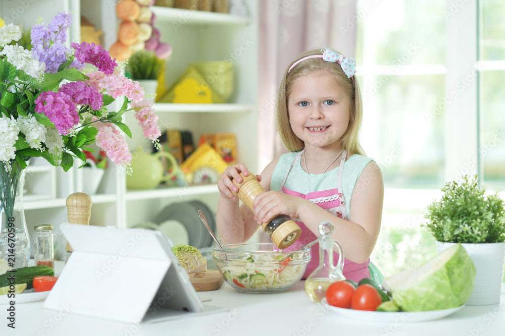 Cute little girl spicing salad on kitchen table Cute little girl spicing salad on kitchen table