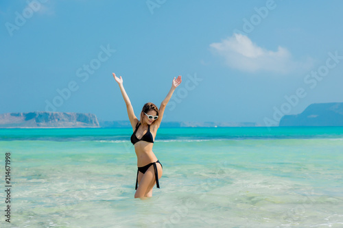 Young redhead girl in black bikini on Balos beach, west Crete, Greece. Summertime season vacation, July
