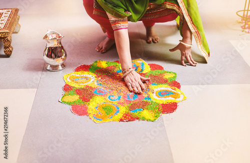 Women coloring traditional rice art (Rangoli) for indian marriage rituals