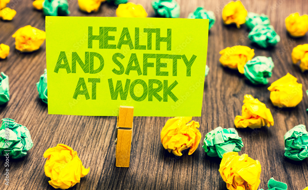 Naklejka premium Handwriting text Health And Safety At Work. Concept meaning Secure procedures prevent accidents avoid danger Paperclip retain written words yellow paper paper lobs laid on wooden floor.
