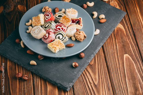 Foto Traditional oriental sweets and nuts: hazelnuts, cashews on a brown wooden background