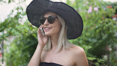 Young stylish beautiful woman in hat using a smart phone. Female talking on the phone