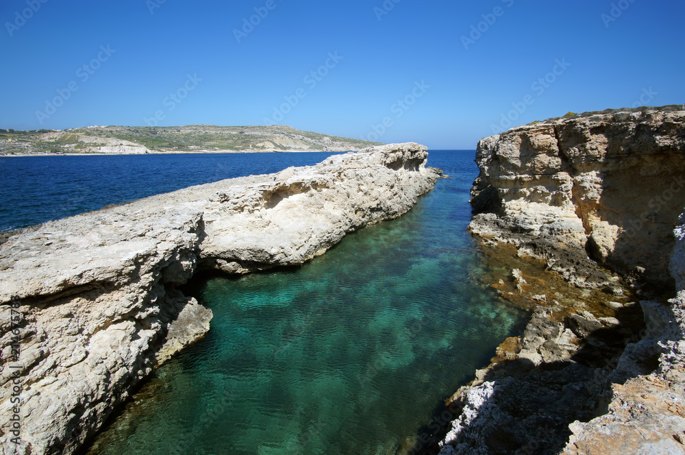 Rocky cliffs of Blue Lagoon in Comino, Malta during the sunny summer day