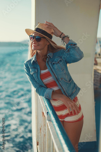 Happy young woman holding hat on cruise ship