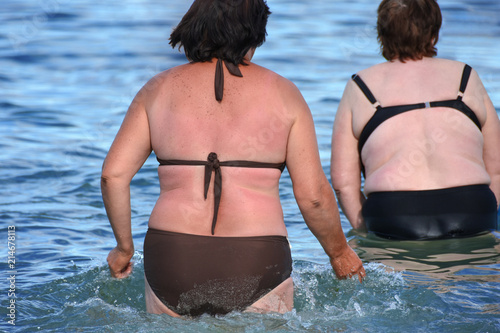 Obraz na plátně Full women in swimsuits swim in the sea water