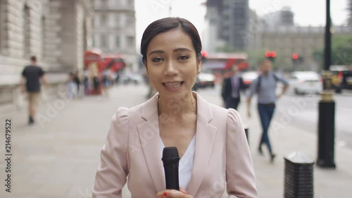 Asian news reporter reporting to camera in the city