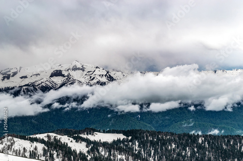 The snow capped mountains are covered with thick clouds