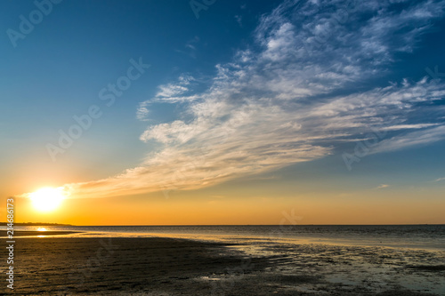 beautiful sunset over the sea shore with clouds reaching the horizon