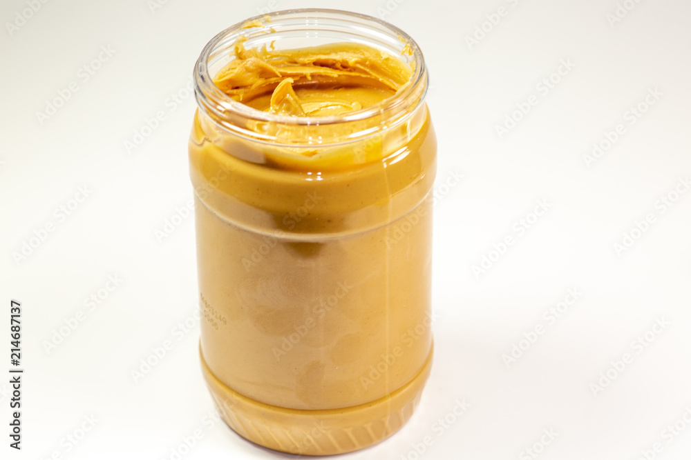 A jar of organic peanut butter sitting on the kitchen table waiting to be eaten A jar of organic peanut butter sitting on the kitchen table waiting to be eaten