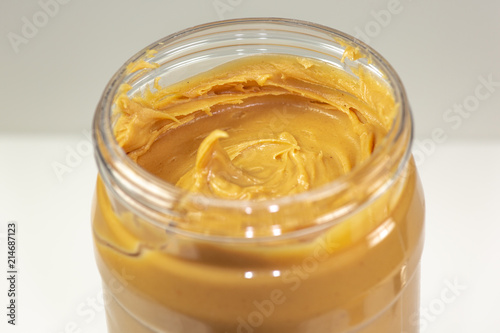 A jar of organic peanut butter sitting on the kitchen table waiting to be eaten 