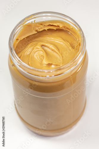 A jar of organic peanut butter sitting on the kitchen table waiting to be eaten 