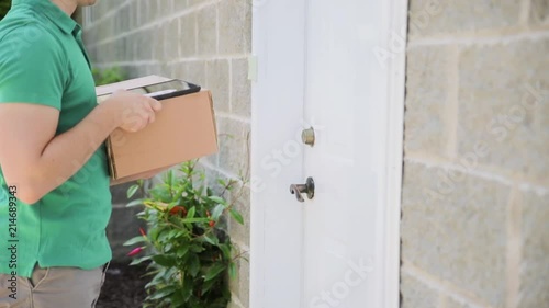 Young woman signing on tablet at the entrance of her home. delivery man brings delivering parcel box