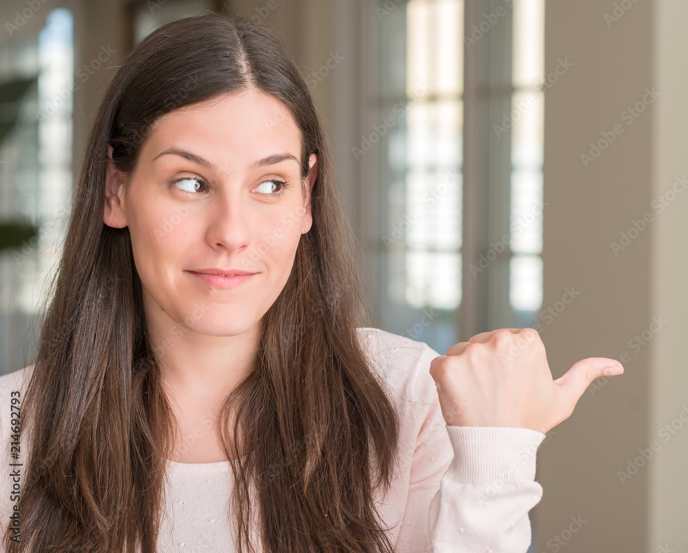 Young beautiful woman at home pointing with hand and finger up with happy face smiling Young beautiful woman at home pointing with hand and finger up with happy face smiling