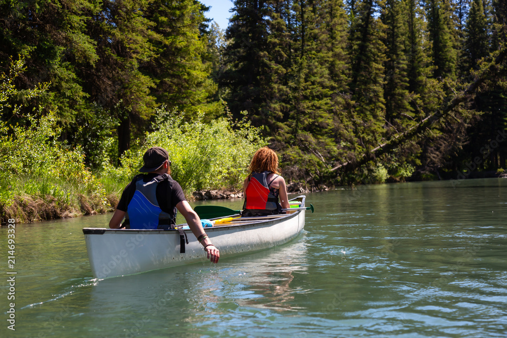 Couple adventurous friends are canoeing in a river surrounded by the Canadian nature. Taken in Vermilion Lakes, Banff, Alberta, Canada.