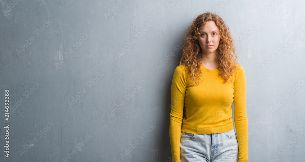 Young redhead woman over grey grunge wall with a confident expression on smart face thinking serious Young redhead woman over grey grunge wall with a confident expression on smart face thinking serious