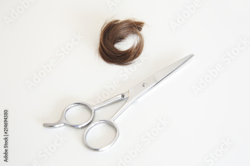 Lock of hair and a haircut scissor in a white background photo