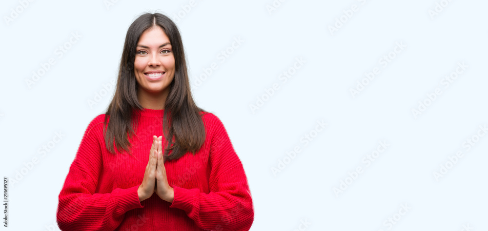 Young beautiful hispanic wearing red sweater praying with hands together asking for forgiveness smiling confident. Young beautiful hispanic wearing red sweater praying with hands together asking for forgiveness smiling confident.