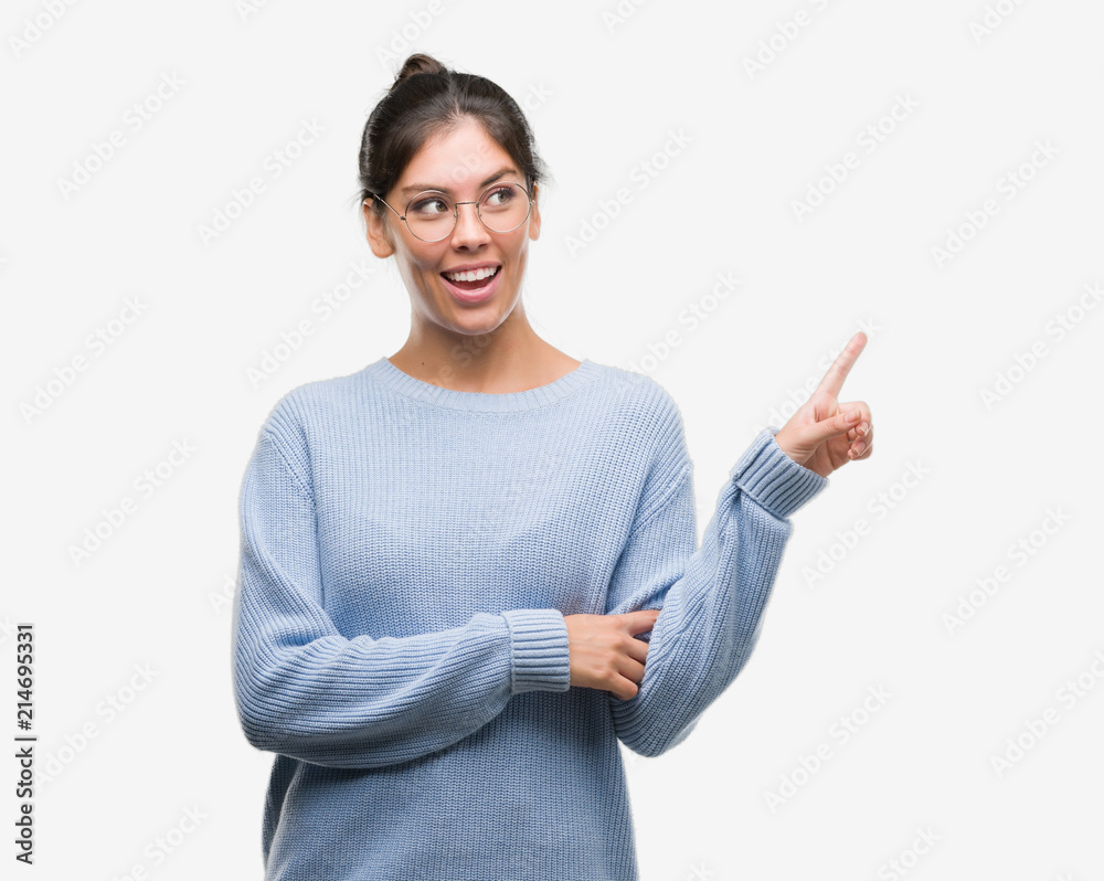 Young beautiful hispanic woman wearing a bun very happy pointing with hand and finger to the side Young beautiful hispanic woman wearing a bun very happy pointing with hand and finger to the side