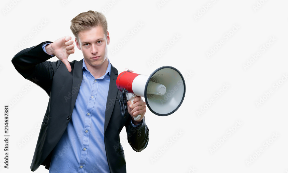 Young handsome blond man holding a megaphone with angry face, negative sign showing dislike with thumbs down, rejection concept Young handsome blond man holding a megaphone with angry face, negative sign showing dislike with thumbs down, rejection concept