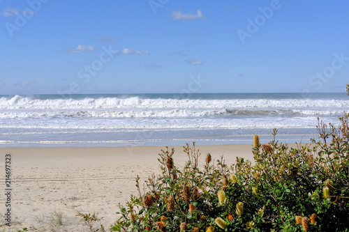 Waves creating spray and foam on an empty Gold Coast beach on a sunny day