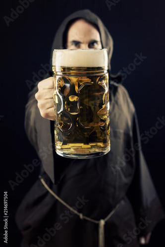 Fototapeta A bearded friar (Franciscan religious man) offering a giant mug of beer to the viewer, made even bigger by the perspective