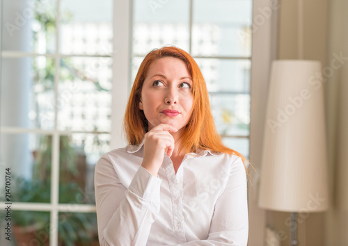 Redhead woman wearing white shirt at home serious face thinking about question, very confused idea