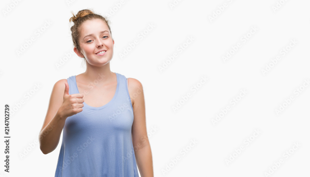 Young blonde woman doing happy thumbs up gesture with hand. Approving expression looking at the camera with showing success. Young blonde woman doing happy thumbs up gesture with hand. Approving expression looking at the camera with showing success.