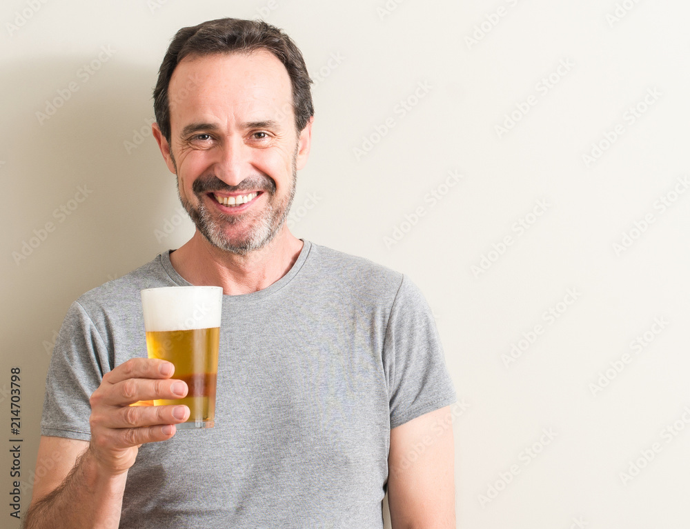 Senior man drinking beer with a happy face standing and smiling with a confident smile showing teeth Senior man drinking beer with a happy face standing and smiling with a confident smile showing teeth