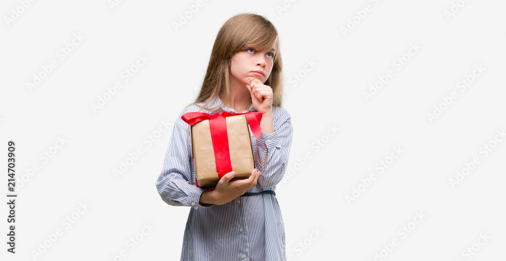 Young blonde toddler holding a present serious face thinking about question, very confused idea Young blonde toddler holding a present serious face thinking about question, very confused idea