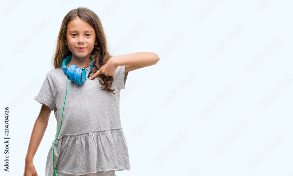 Brunette hispanic girl wearing headphones with surprise face pointing finger to himself Brunette hispanic girl wearing headphones with surprise face pointing finger to himself