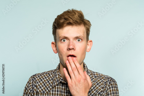 surprised startled amazed astounded man. gasping with astonishment. portrait of a young guy on light background. emotion facial expression. people reaction concept. photo