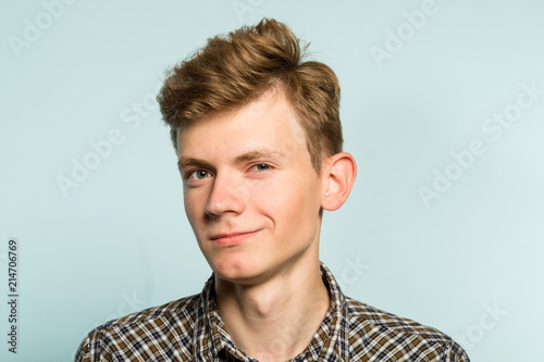 smug handsome guy with a mysterious smile. cute geek or dork. portrait of a young guy on light background. emotion facial expression. feelings and people reaction. photo