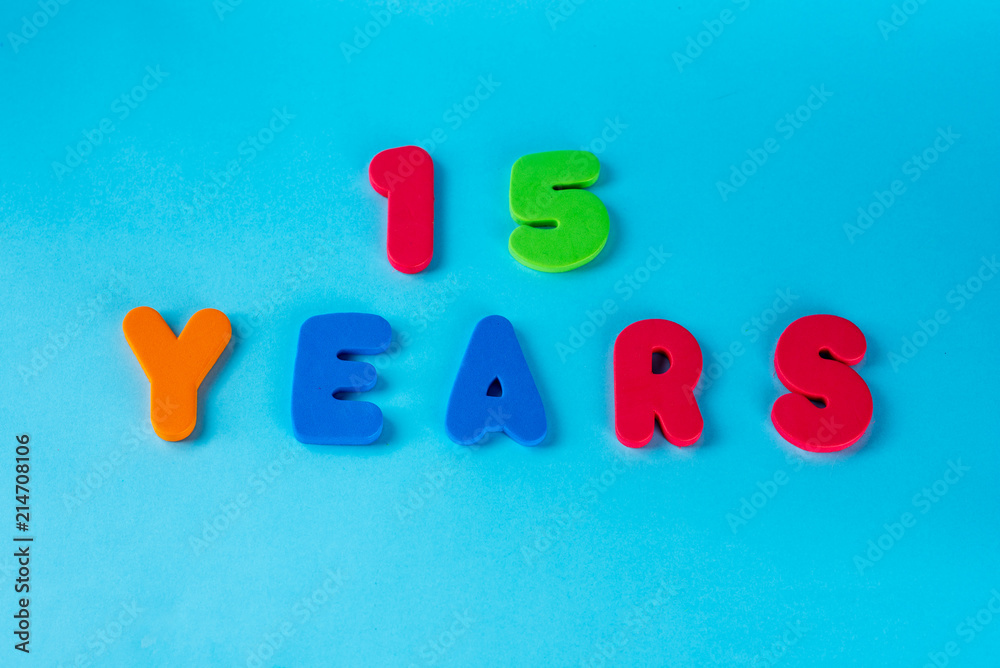 Naklejka premium 15 years old celebrating classic logo. Colored happy anniversary 15 th colored numbers on blue background. Greetings celebrates card. Traditional digits of ages. Flat lay .