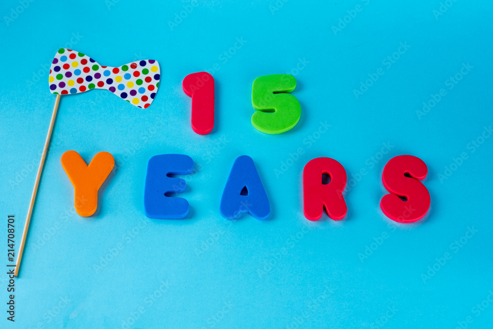 Naklejka premium 15 years old celebrating classic logo. Colored happy anniversary 15 th colored numbers on blue background. Greetings celebrates card. Traditional digits of ages. Flat lay .