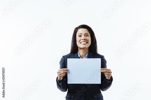 Portrait of a woman with big smile and grey jacket holding blank sign, isolated on white studio background