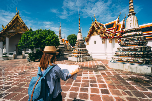 Young woman traveler with backpack and hat looking the Map in Wat Pho at Bangkok Thailand. Traveling in Bangkok Thailand