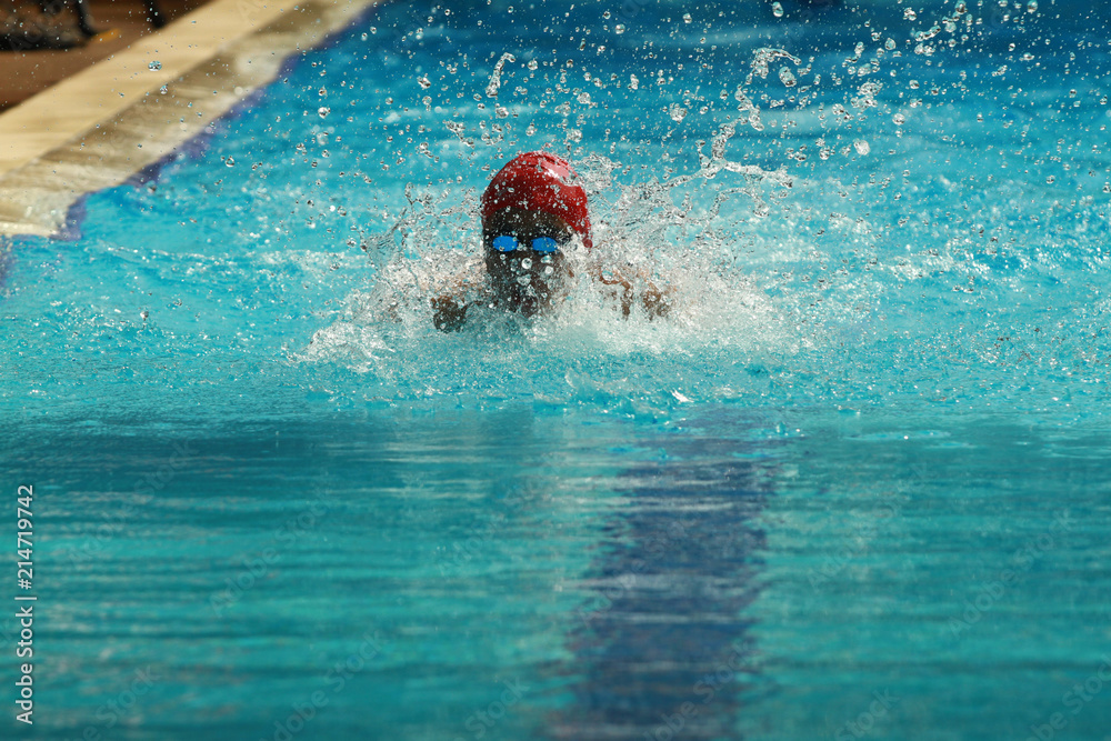 Swimmer wearing red cap practice butterfly stroke in a swimming pool for competition or race