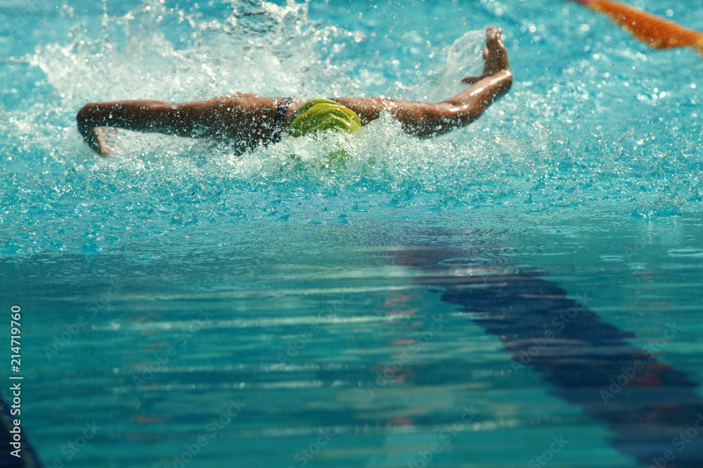 Swimmer wearing yellow cap practice butterfly stroke in a swimming pool for competition or race