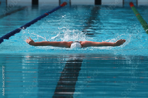 Swimmer wearing white cap practice butterfly stroke in a swimming pool for competition or race