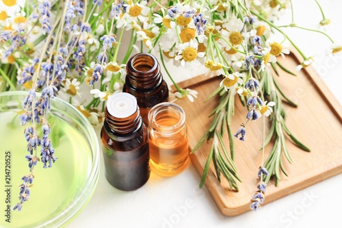 Aromatherapy set with different holistic fresh herbs and extracts, bottles and flowers, soft natural light. 