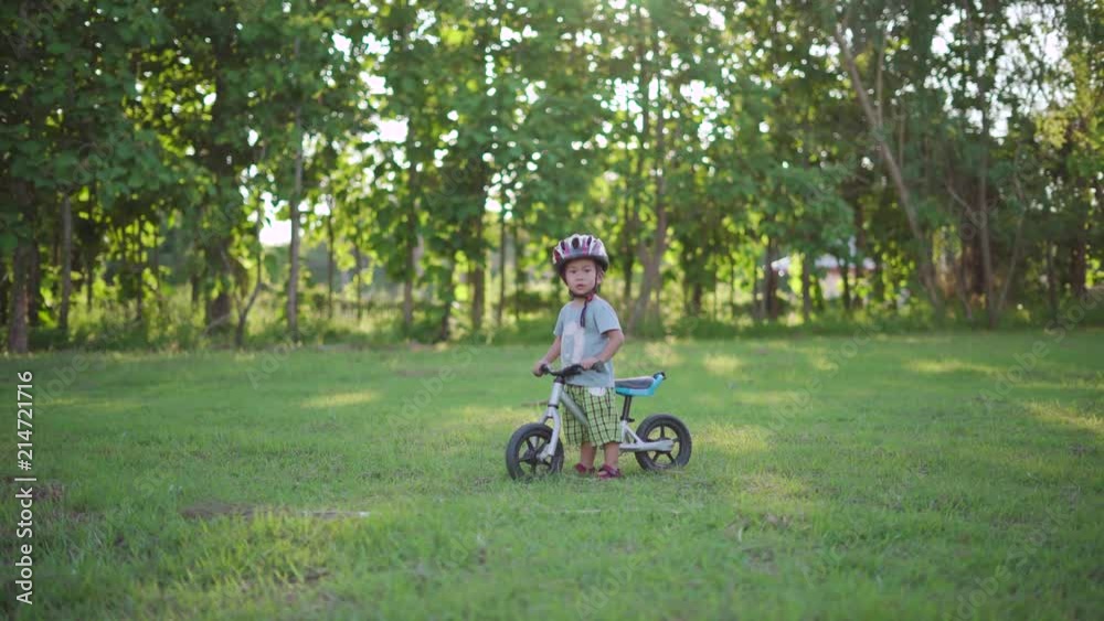 Asian boy about 2 year and 4 months is riding baby balance bike at football field in Thai public school Asian boy about 2 year and 4 months is riding baby balance bike at football field in Thai public school