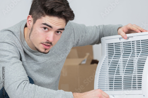 handsome young man electrician installing air conditioning in client house