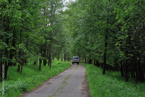 Moscow region, Russia. National Park "Elk island". The car with the forester goes on a single-lane road in the forest